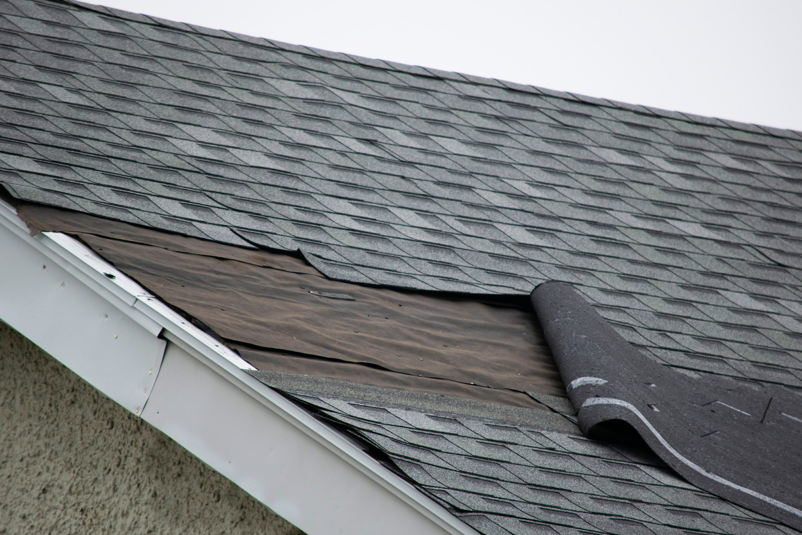 Roof with visible signs of winter damage, such as missing shingles and ice dam